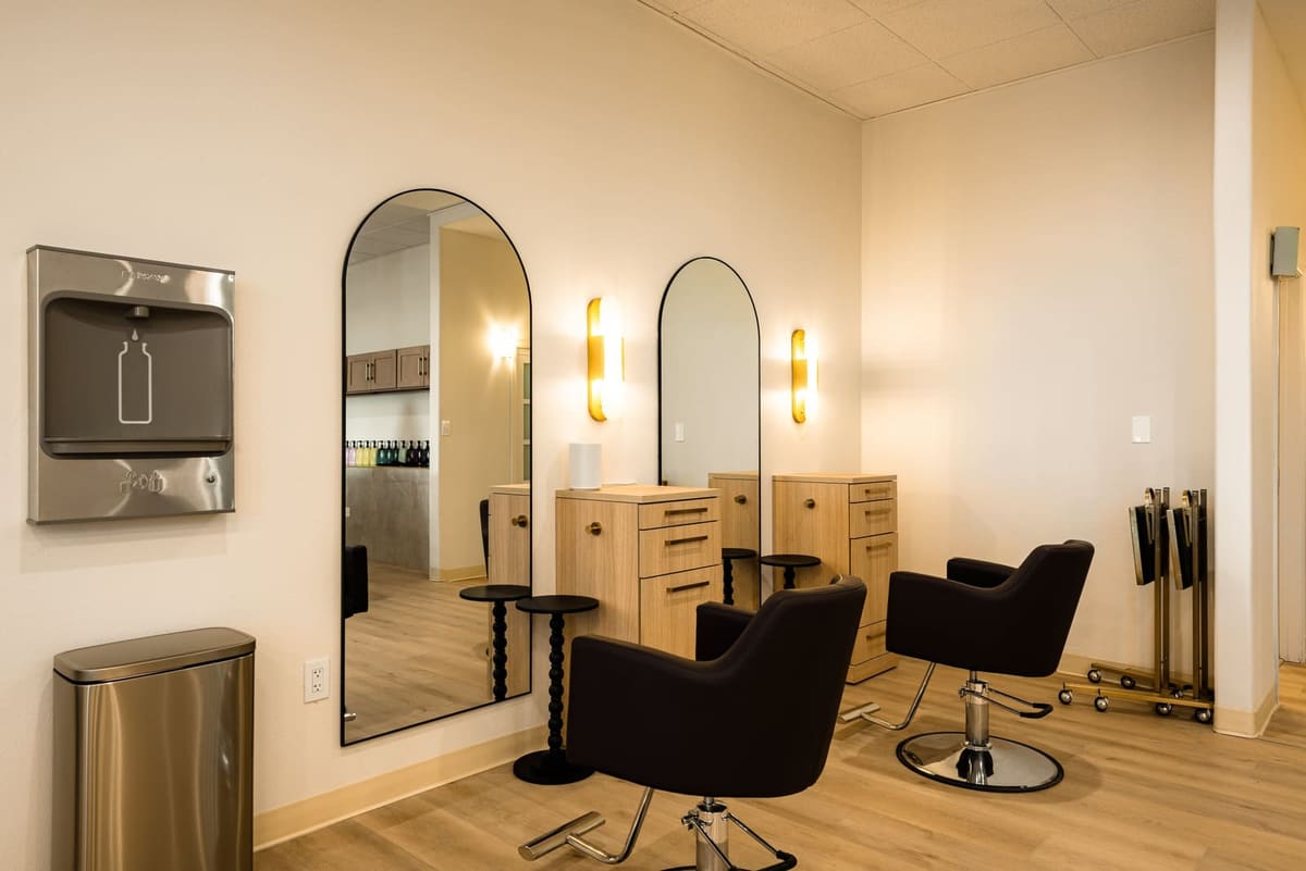 Styling stations with tall arched black mirrors, brass sconces and black salon chairs