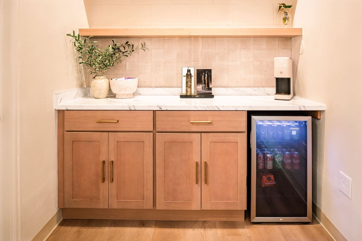 Staff break area with oak shaker cabinets, quartz counter, beverage fridge and a floating shelf