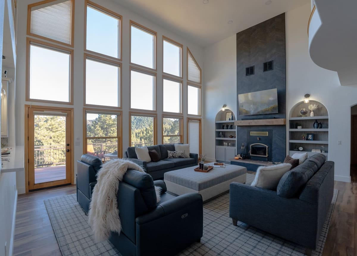 Living room with a two-story wall of windows, navy sofas, leather recliners and a charcoal chevron-tile fireplace