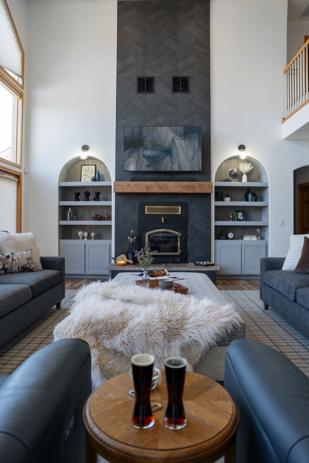 Living room fireplace wall in charcoal chevron tile with a reclaimed beam mantel and gray built-ins in arched niches
