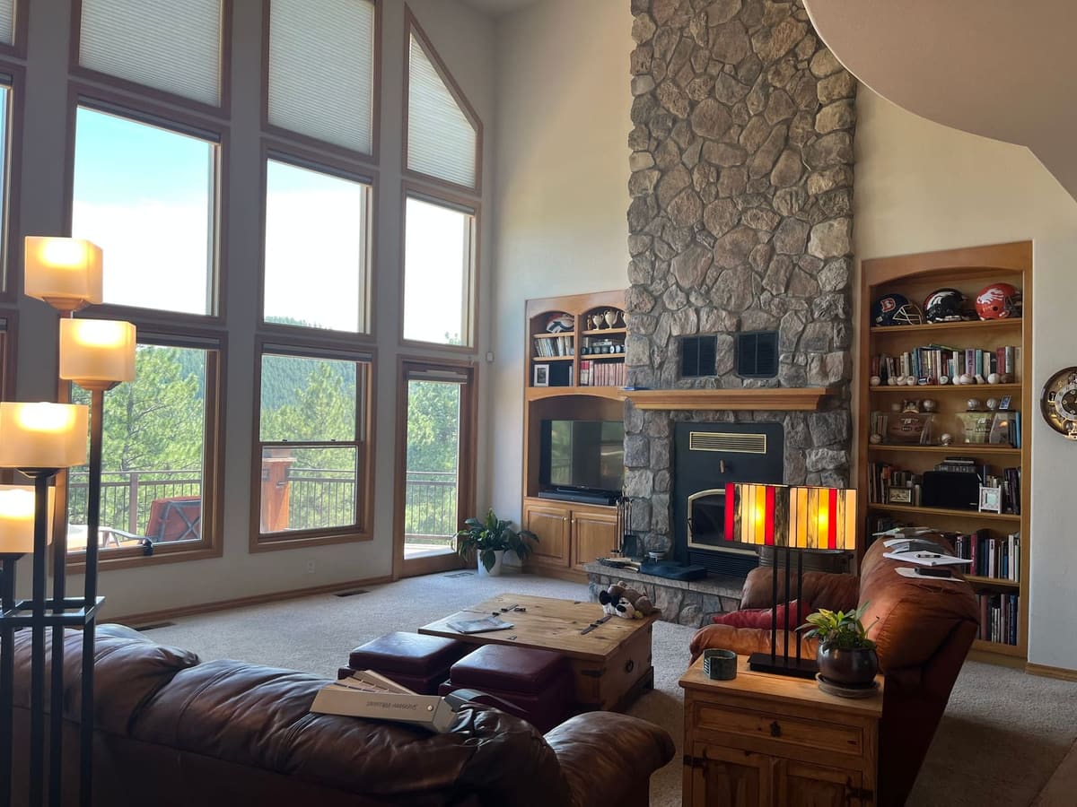 Before the remodel: living room with a floor-to-ceiling stone fireplace, oak built-ins and brown leather sofas