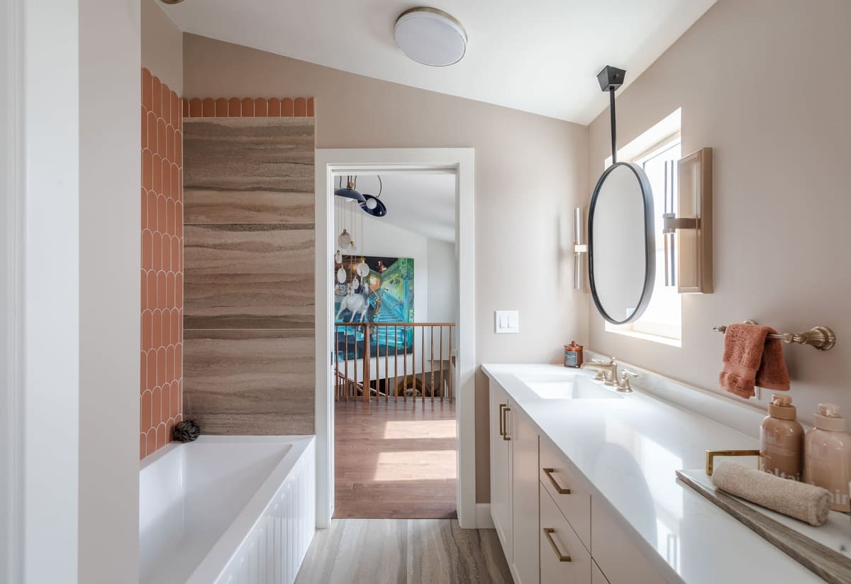 Bathroom with a fluted tub, terracotta scallop tile, striated porcelain shower wall and an oval hanging mirror