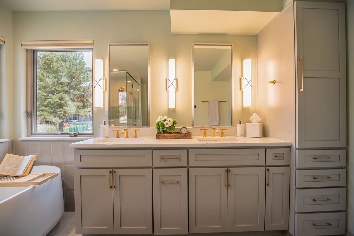Gray shaker double vanity with a linen tower, nickel framed mirrors, X-detail sconces and brass faucets