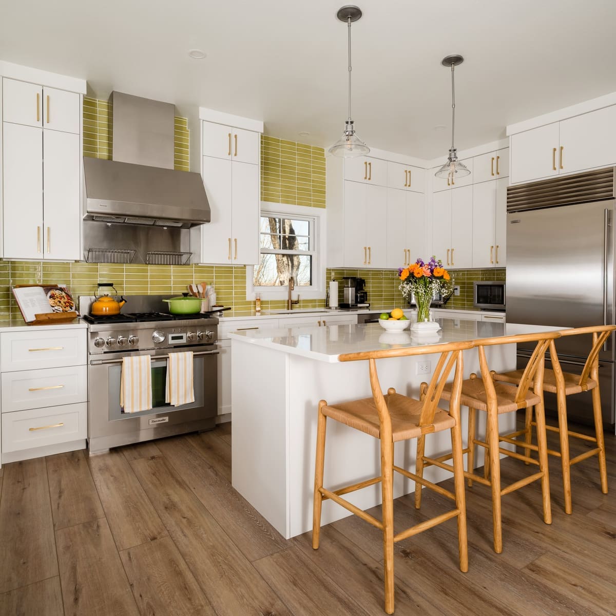 Kitchen with white slab and shaker cabinets, chartreuse stacked tile, a pro range and woven wishbone stools