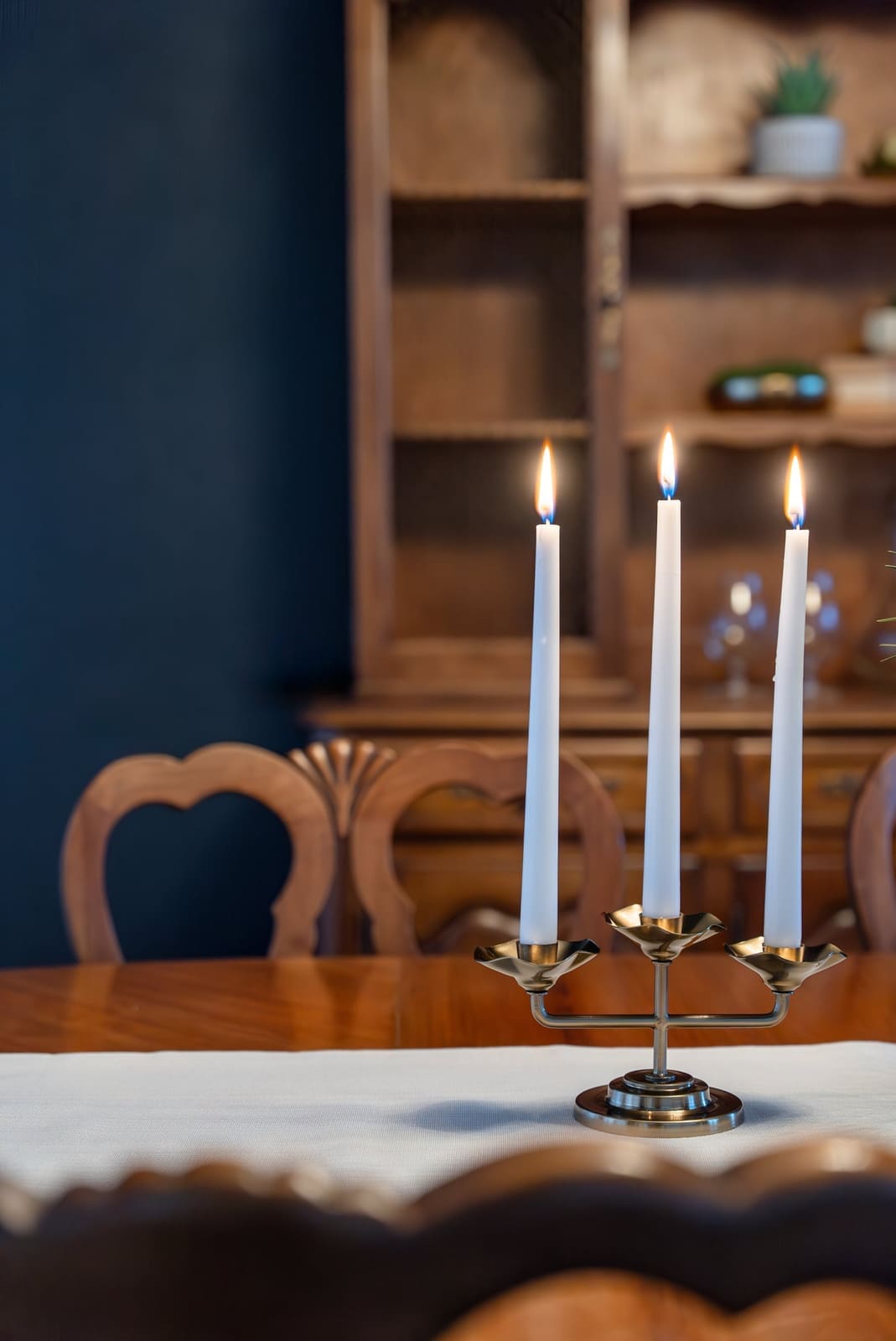 Close view of a brass candelabra with taper candles on the dining table in a navy-walled dining room