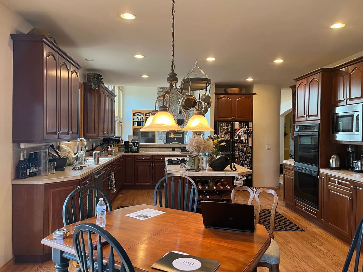 Before the remodel: kitchen with cherry cabinets, tile counters and a hanging pot rack over the island