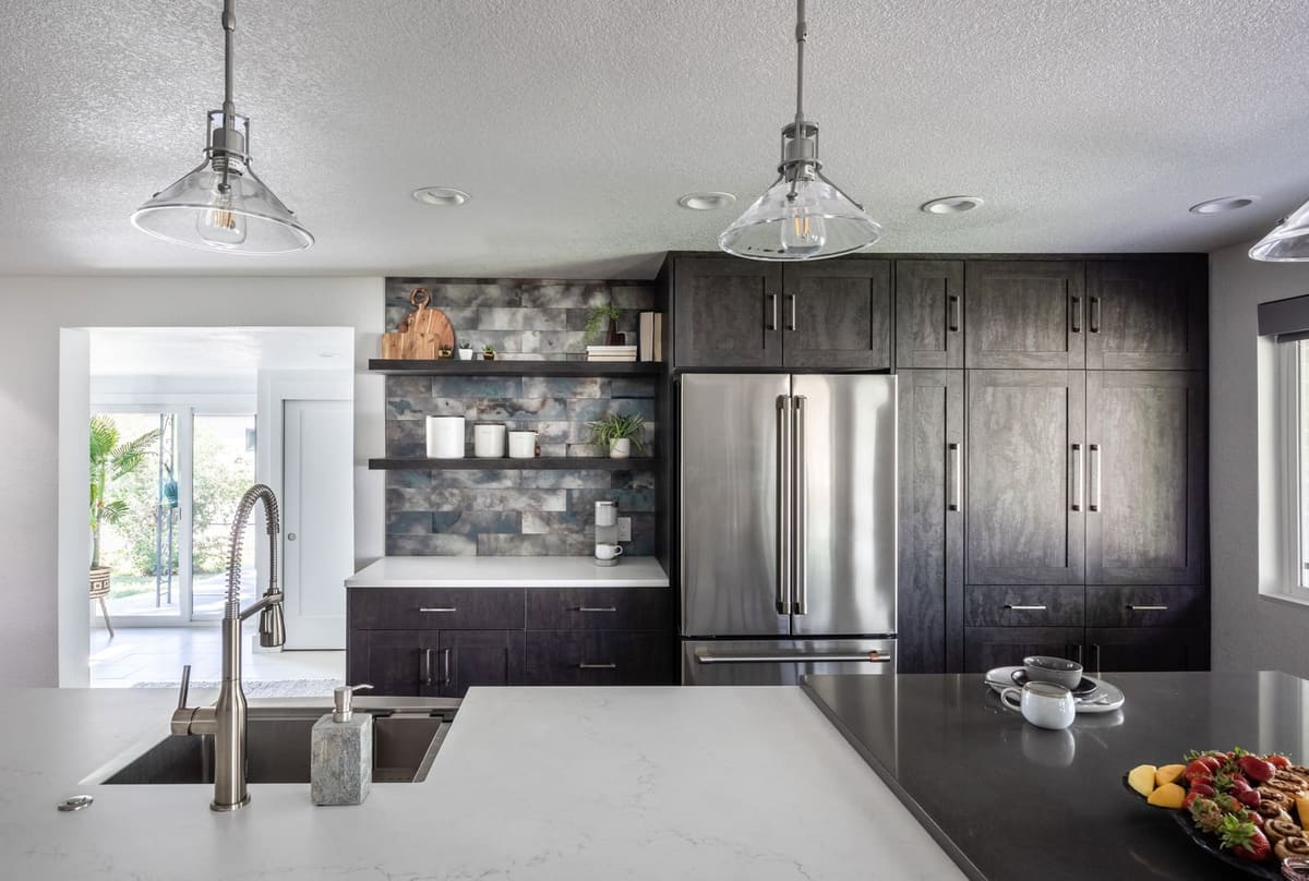 Charcoal-stained pantry wall with a stainless refrigerator and open shelves on smoky glass tile