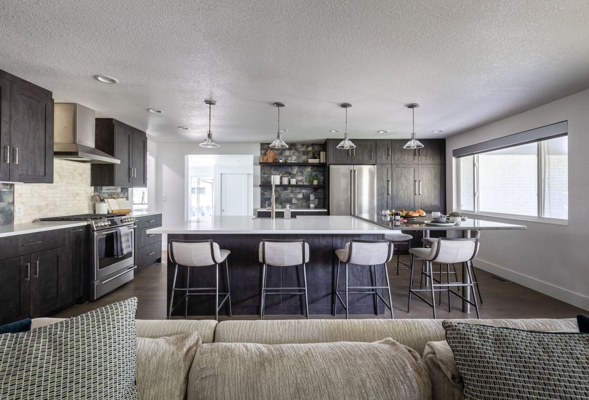 Charcoal kitchen with open shelving on a smoky tile wall, seen across the living room sofa