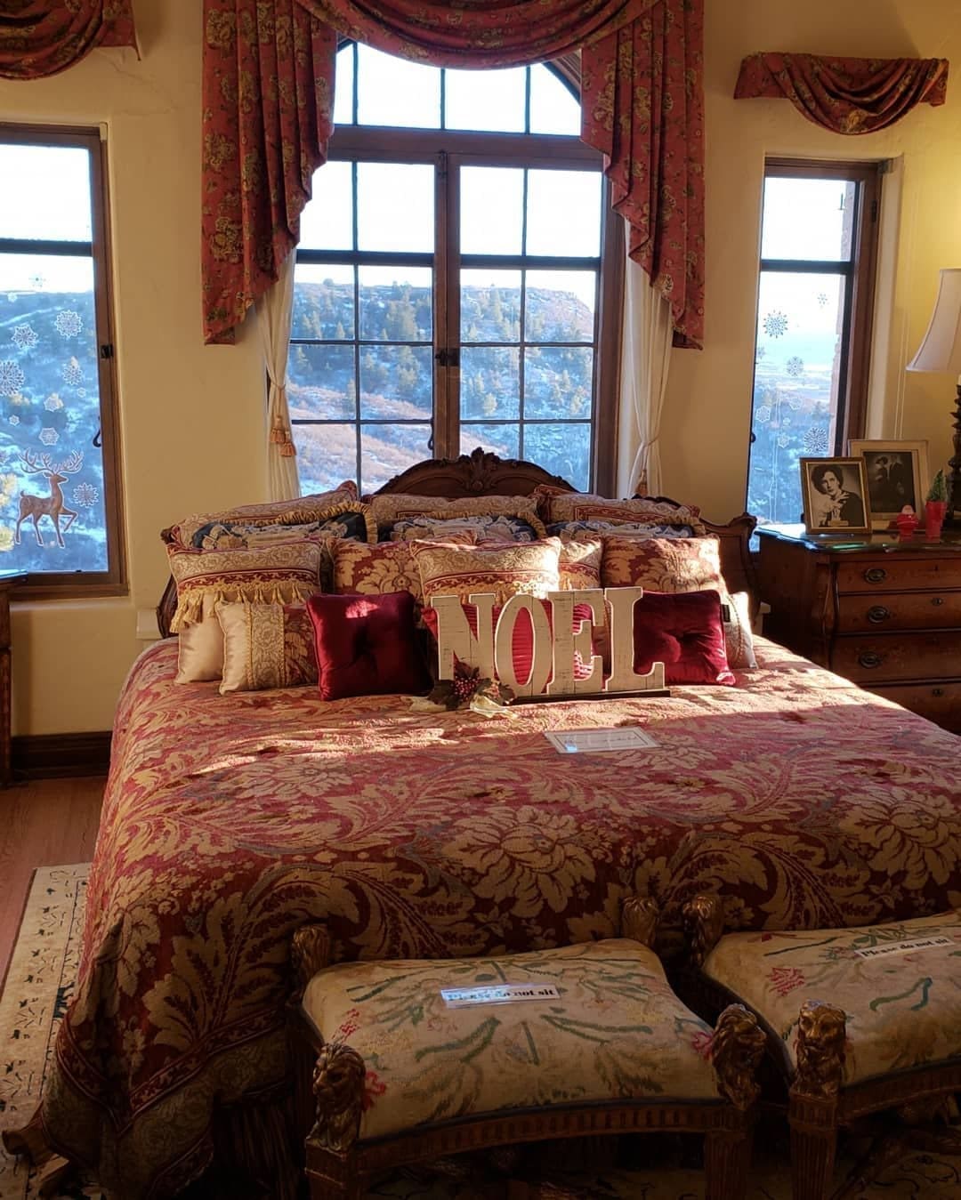 Guest bedroom dressed for the holidays with a NOEL pillow, red and gold bedding and swagged window drapes
