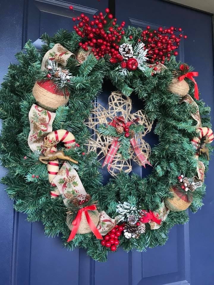Front door wreath of fir, red berries, pinecones and plaid and burlap ribbon on a navy door