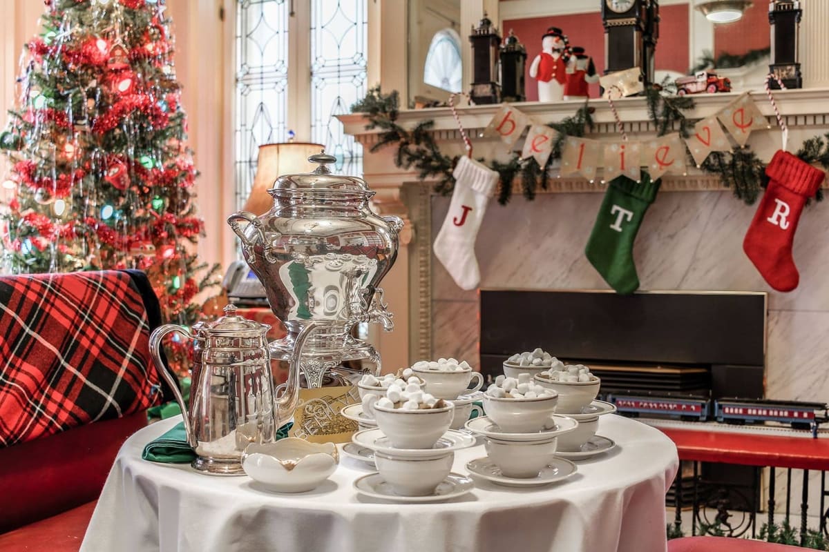 Silver cocoa service on a white-draped table in front of a garlanded mantel with monogrammed stockings at the Colorado Governor's Mansion