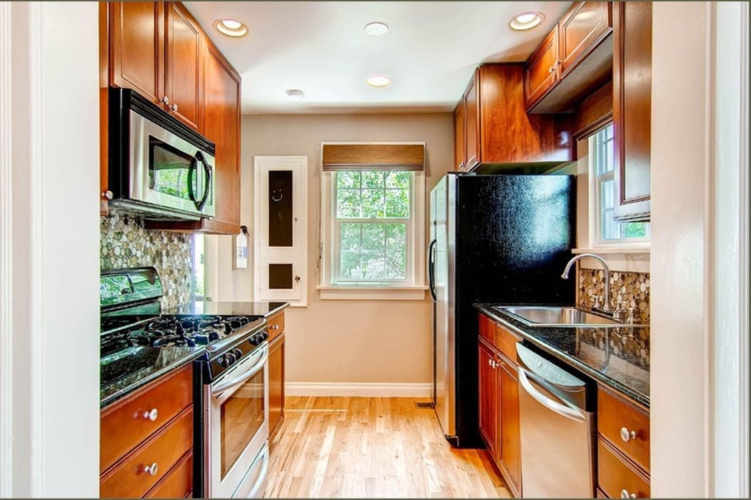 Before the remodel: narrow kitchen with cherry cabinets, black granite and black appliances