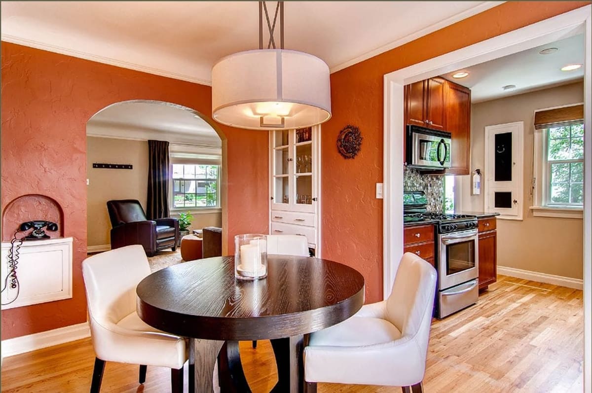Before the remodel: orange-walled dining room with a round table opening into a cherry kitchen