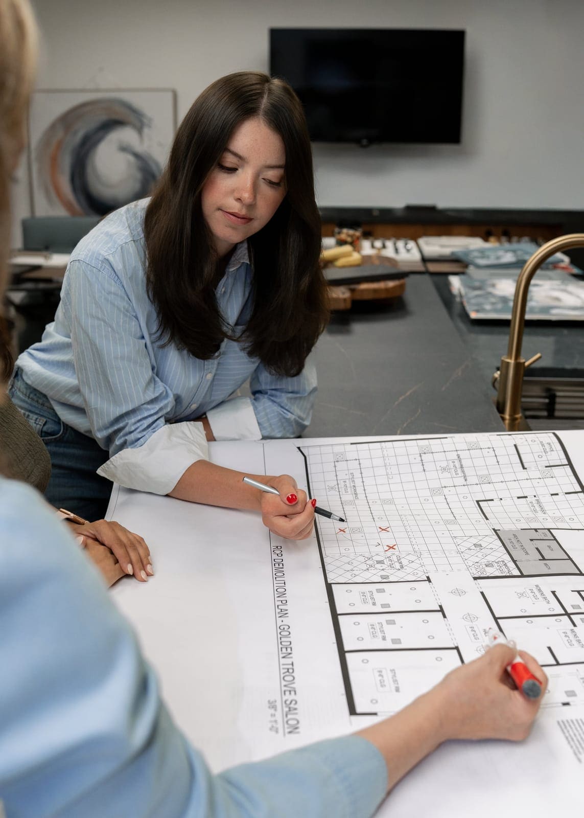 Gabby Hinchey marking up a printed floor plan with a red pen at the TAB studio table