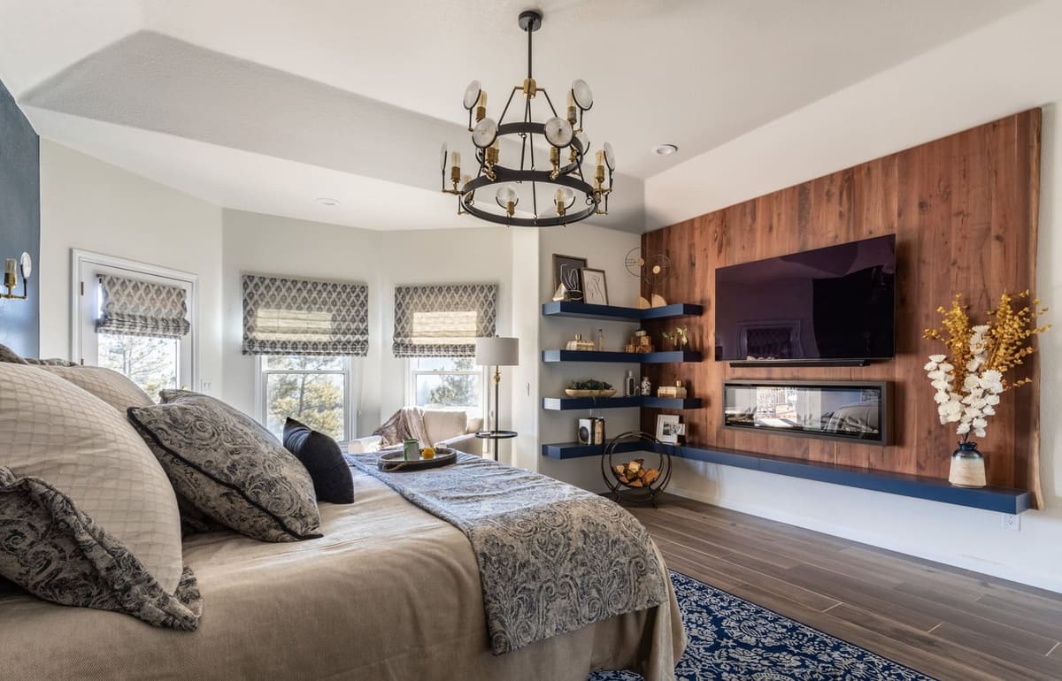 Primary bedroom with a wood-plank media wall, linear fireplace and navy floating shelves