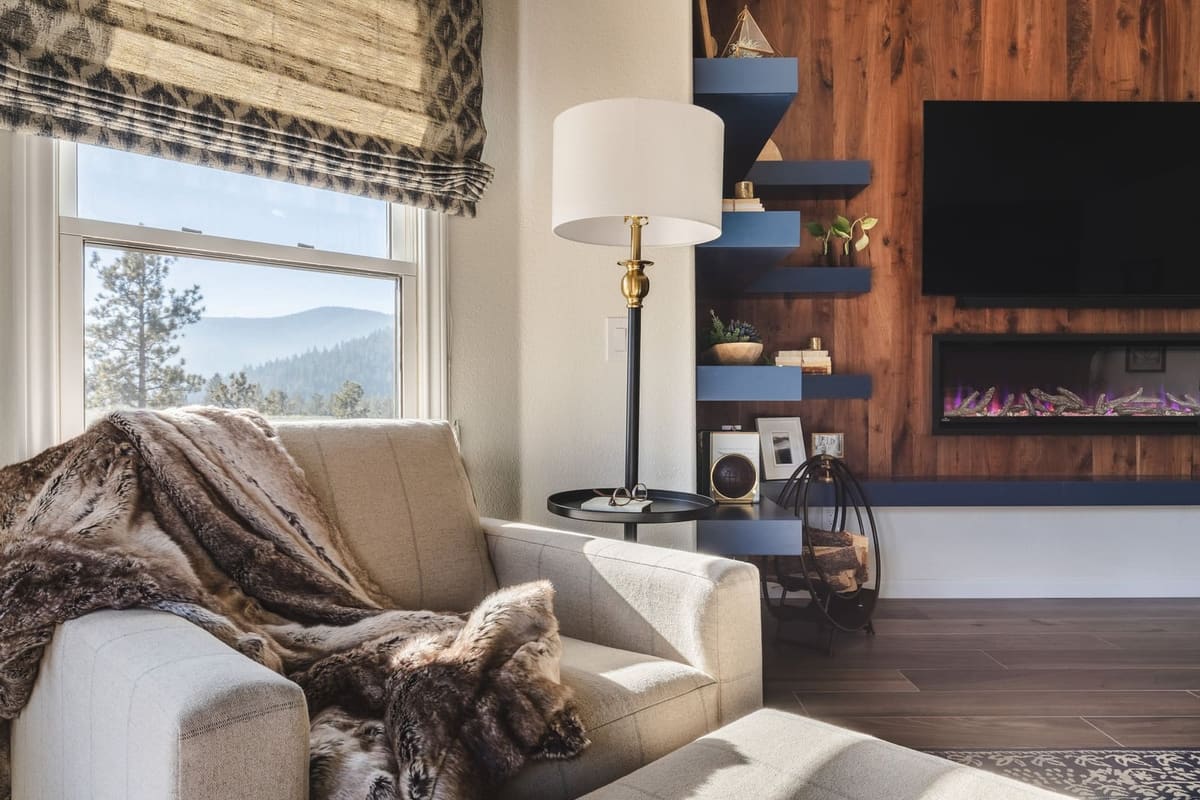 Cream armchair with a faux fur throw by a mountain-view window and the wood-plank fireplace wall