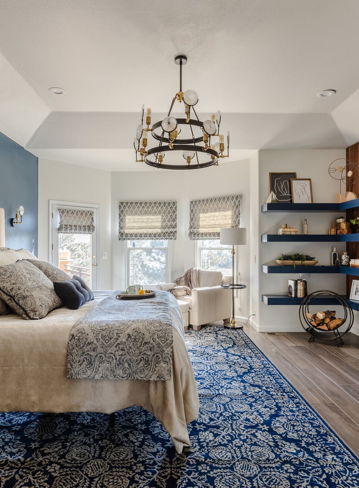 Primary bedroom bay window with a seating area, navy floating shelves and a wagon-wheel chandelier