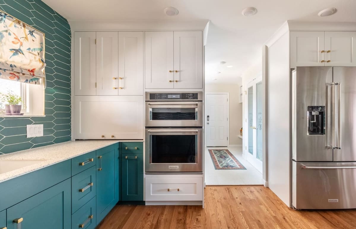 Teal and white kitchen wall with double wall ovens, a stainless refrigerator and teal picket tile