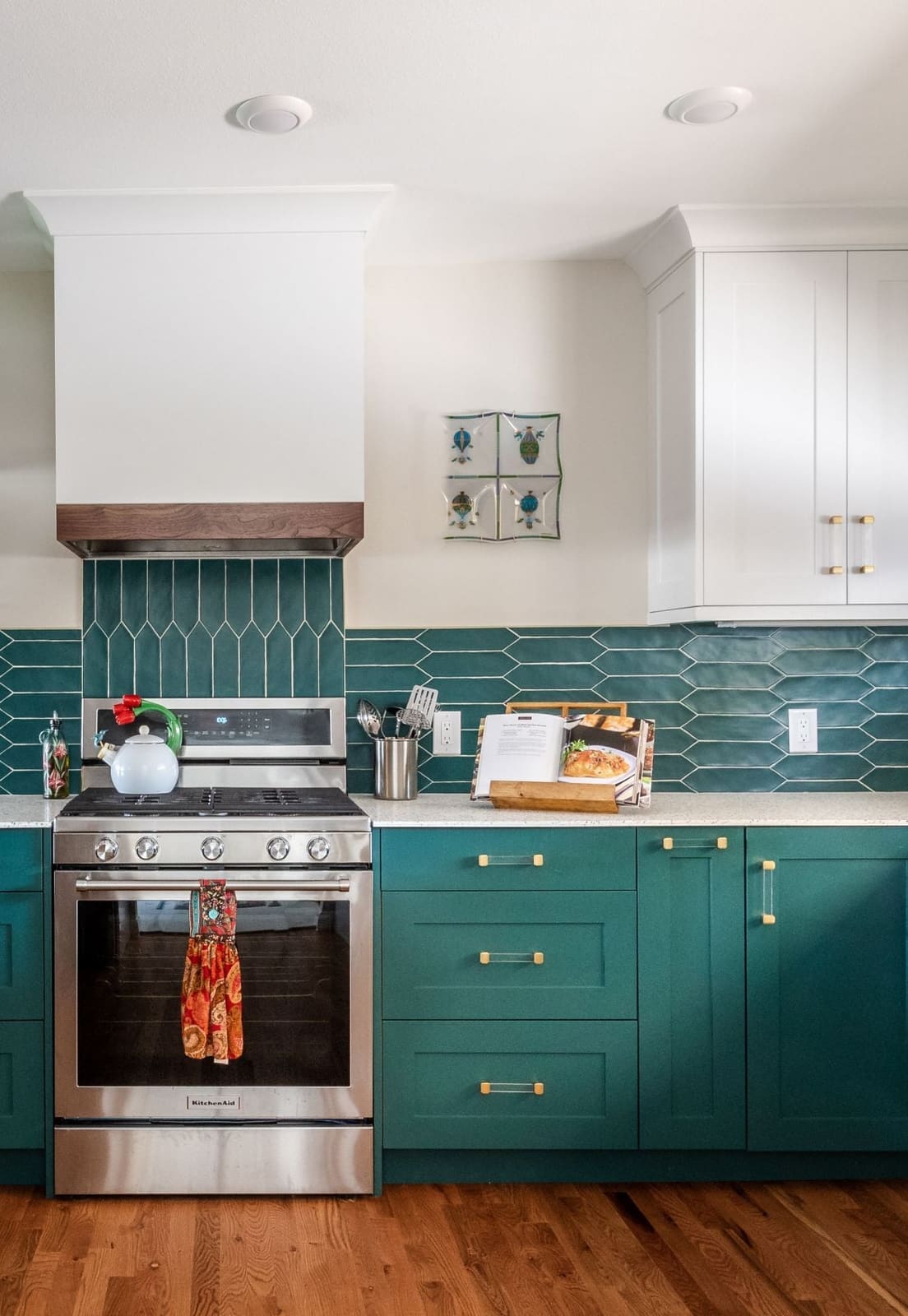 Stainless range under a white hood with a walnut band and teal picket tile backsplash