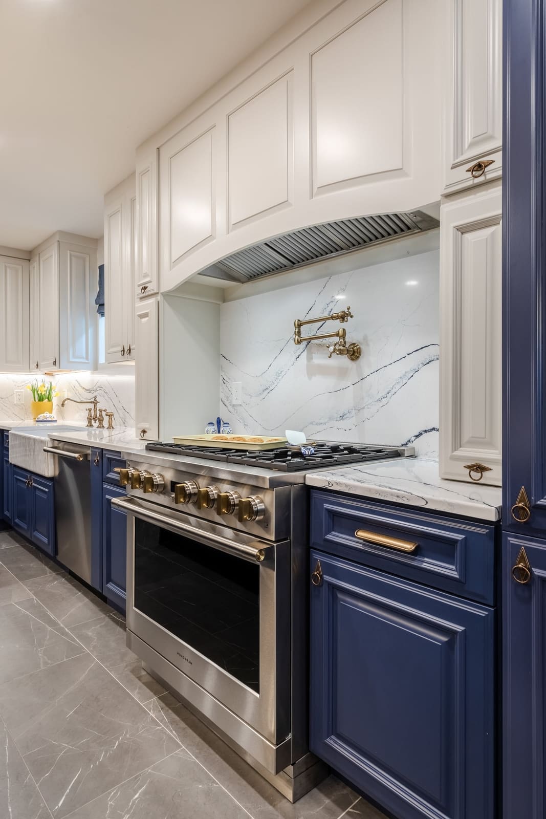 Pro range with a pot filler under a white hood and a book-matched quartz slab backsplash