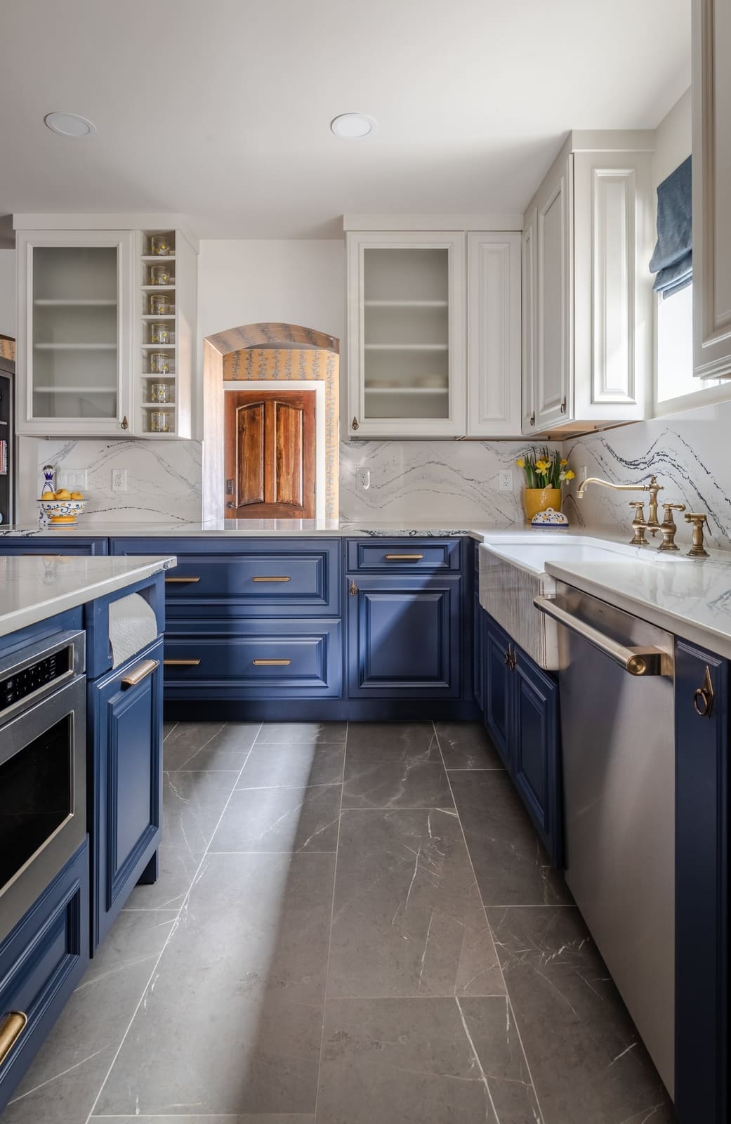 Navy and white side of the kitchen with glass-front uppers and a dishwasher