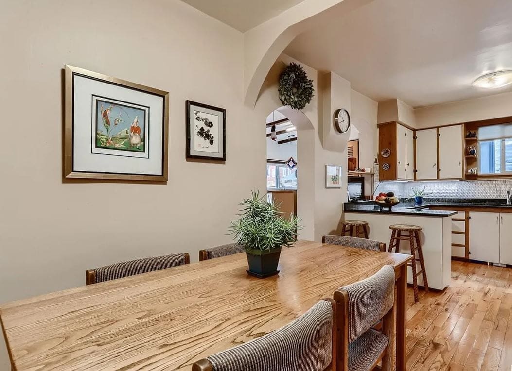 Before the remodel: dining nook with a wood table and framed prints, the old kitchen through an arch