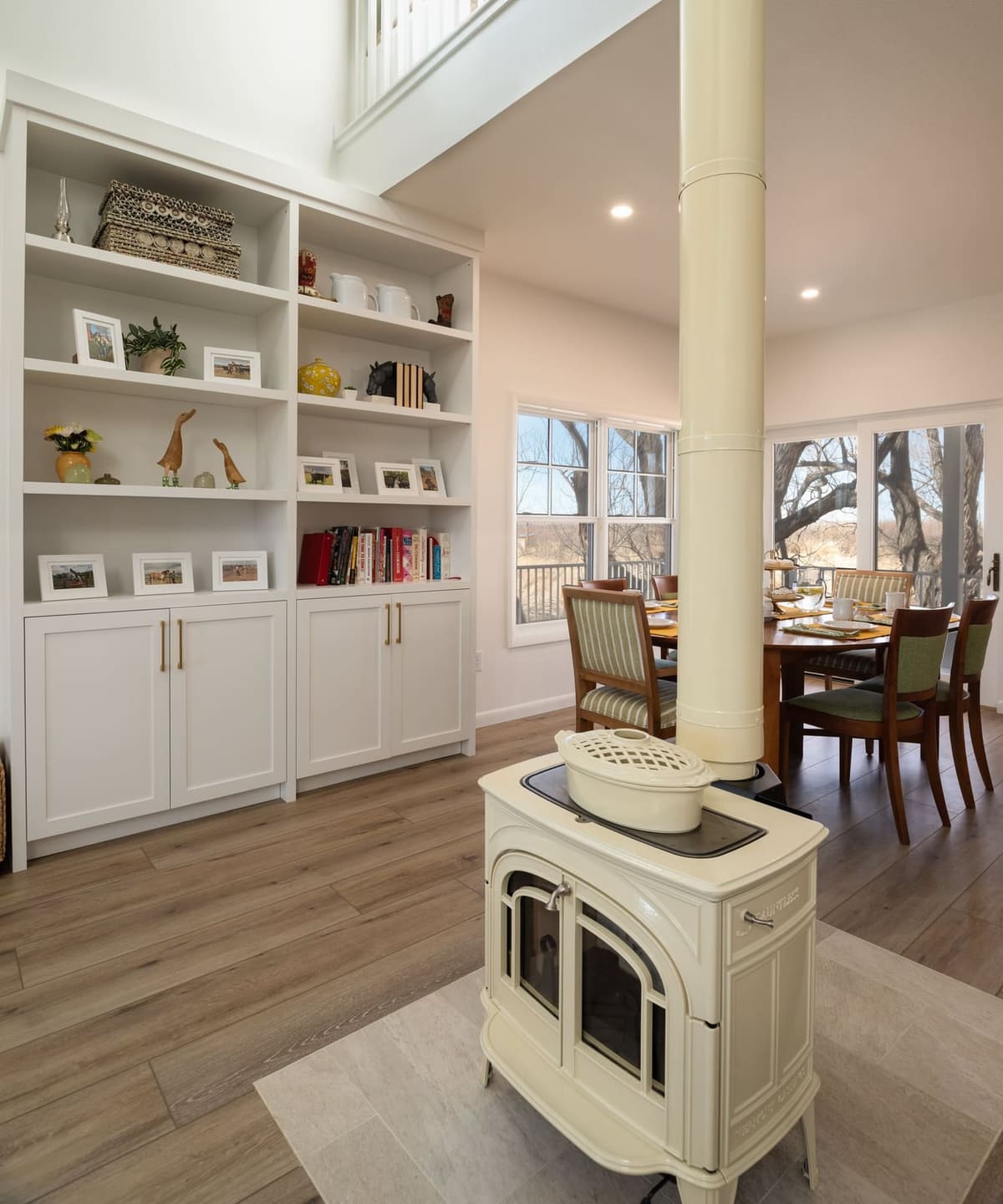 Cream wood stove in front of built-in white bookshelves with the dining table by the windows