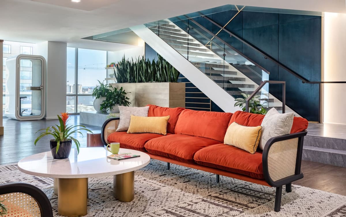 Orange sofa with mustard pillows and a round white coffee table beside the planted feature stair