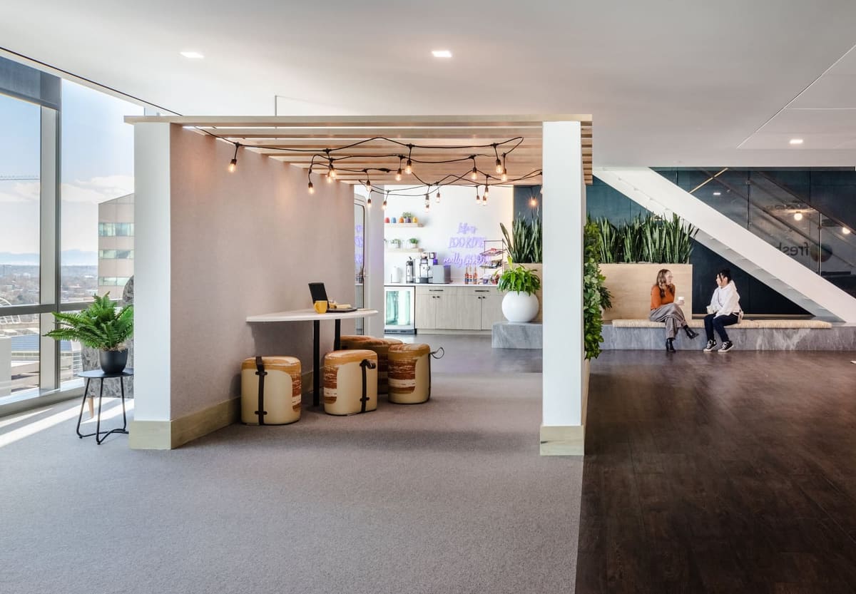 Slatted-ceiling café nook opening onto the planted stair landing of a high-rise office