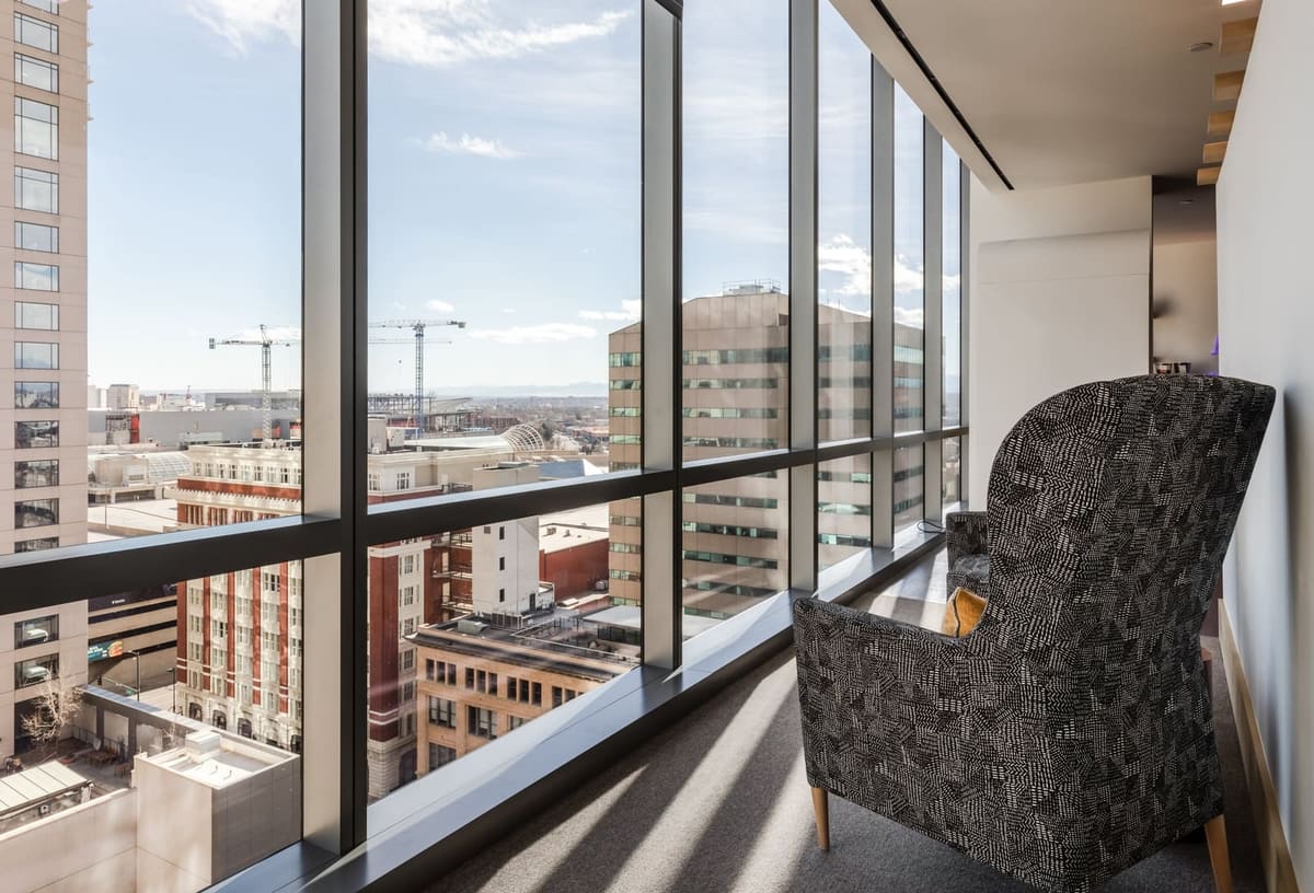 Patterned wingback chair beside floor-to-ceiling windows overlooking downtown