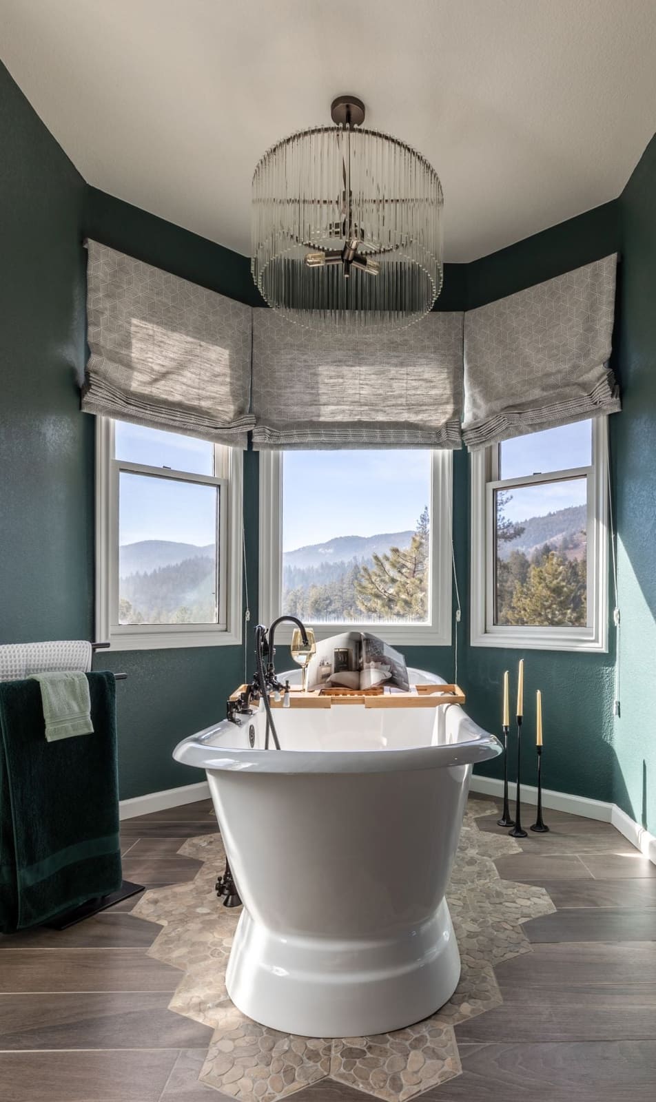 Freestanding tub on hexagon tile in a green bay window under a glass globe chandelier