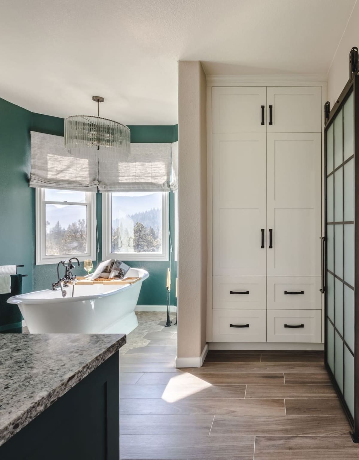 Primary bath with a freestanding tub, white linen cabinet and frosted glass door