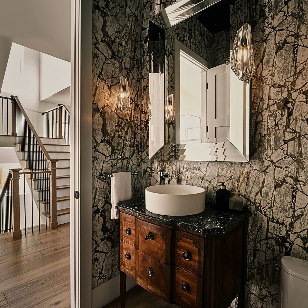 Powder room with black and white marble-look wallpaper, an antique wood vanity and a white vessel sink