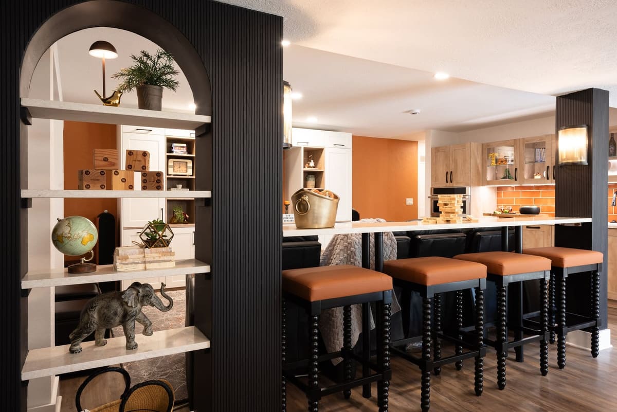 Basement bar counter with four cognac leather stools, an arched shelf divider and orange walls beyond
