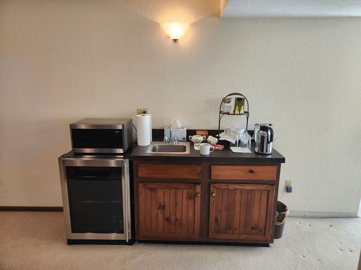 Before the remodel: basement sink cabinet in knotty pine with a laminate top beside a mini fridge
