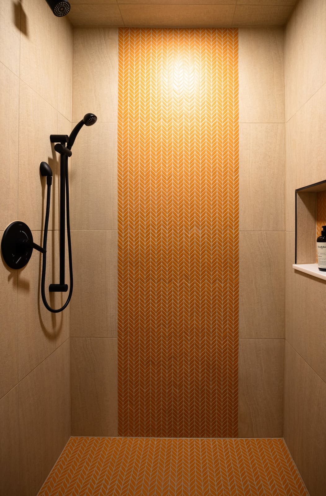 Shower with a column of orange chevron tile between cream panels and a black hand shower