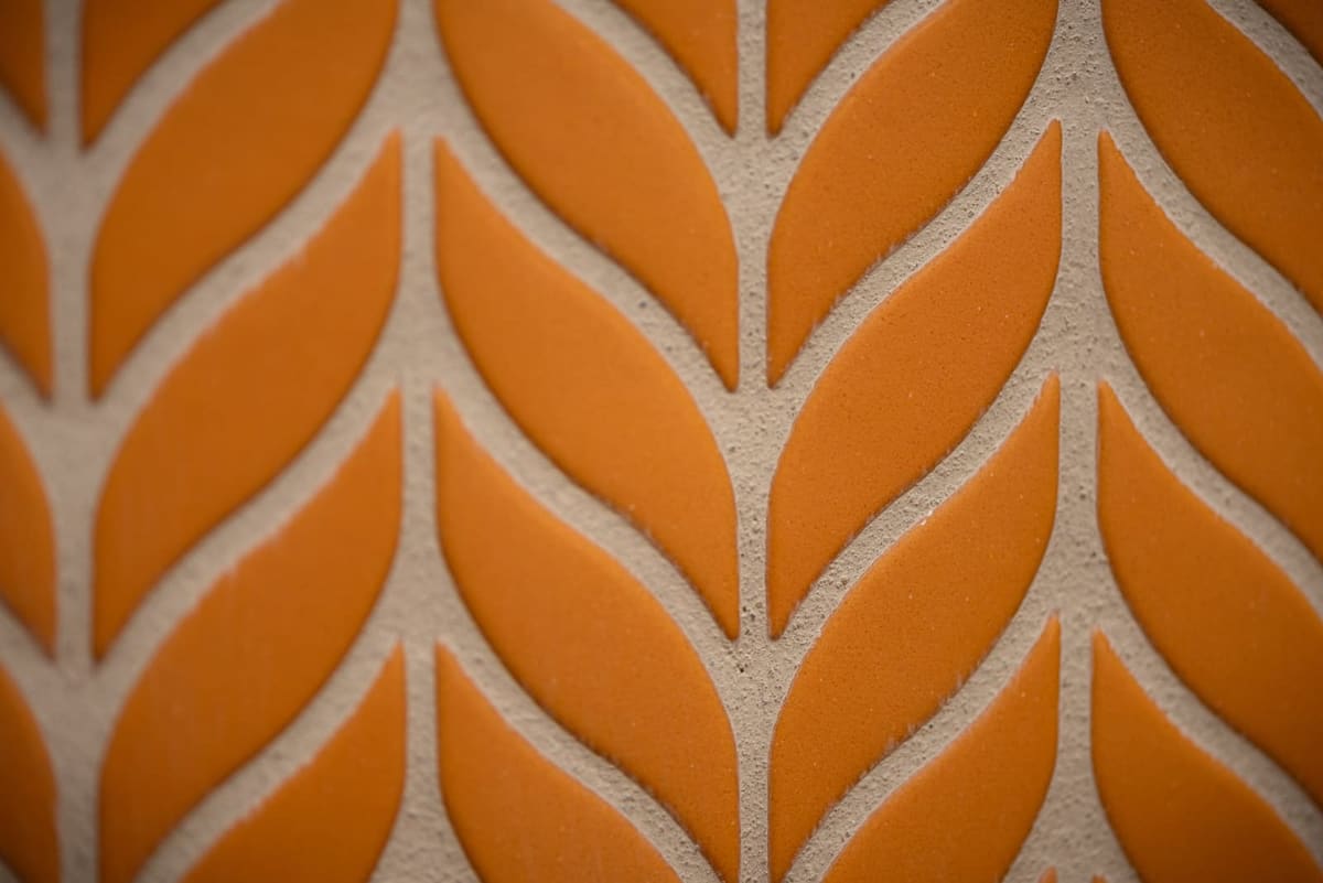 Close-up of orange leaf-shaped chevron mosaic tile set in white grout