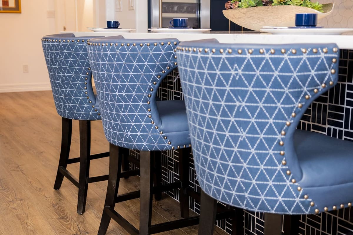 Row of blue geometric upholstered stools with nailhead trim at the island