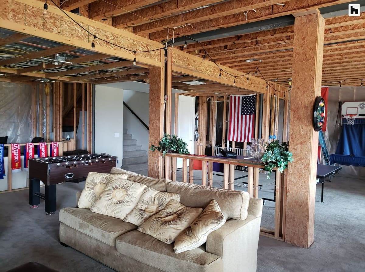 Before the remodel: unfinished basement with exposed joists, a foosball table and an old sofa