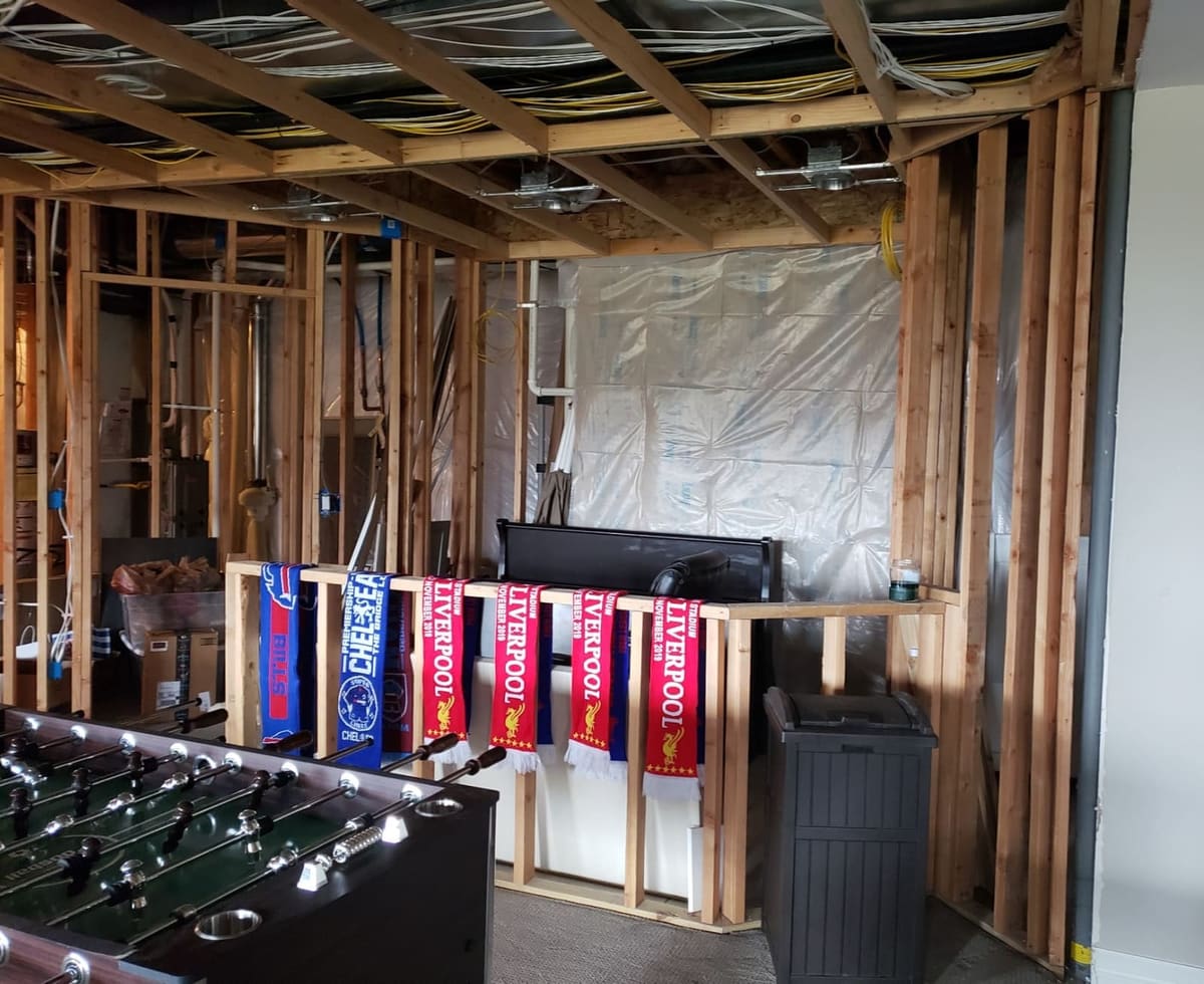 Before the remodel: framed basement walls and exposed joists around a foosball table
