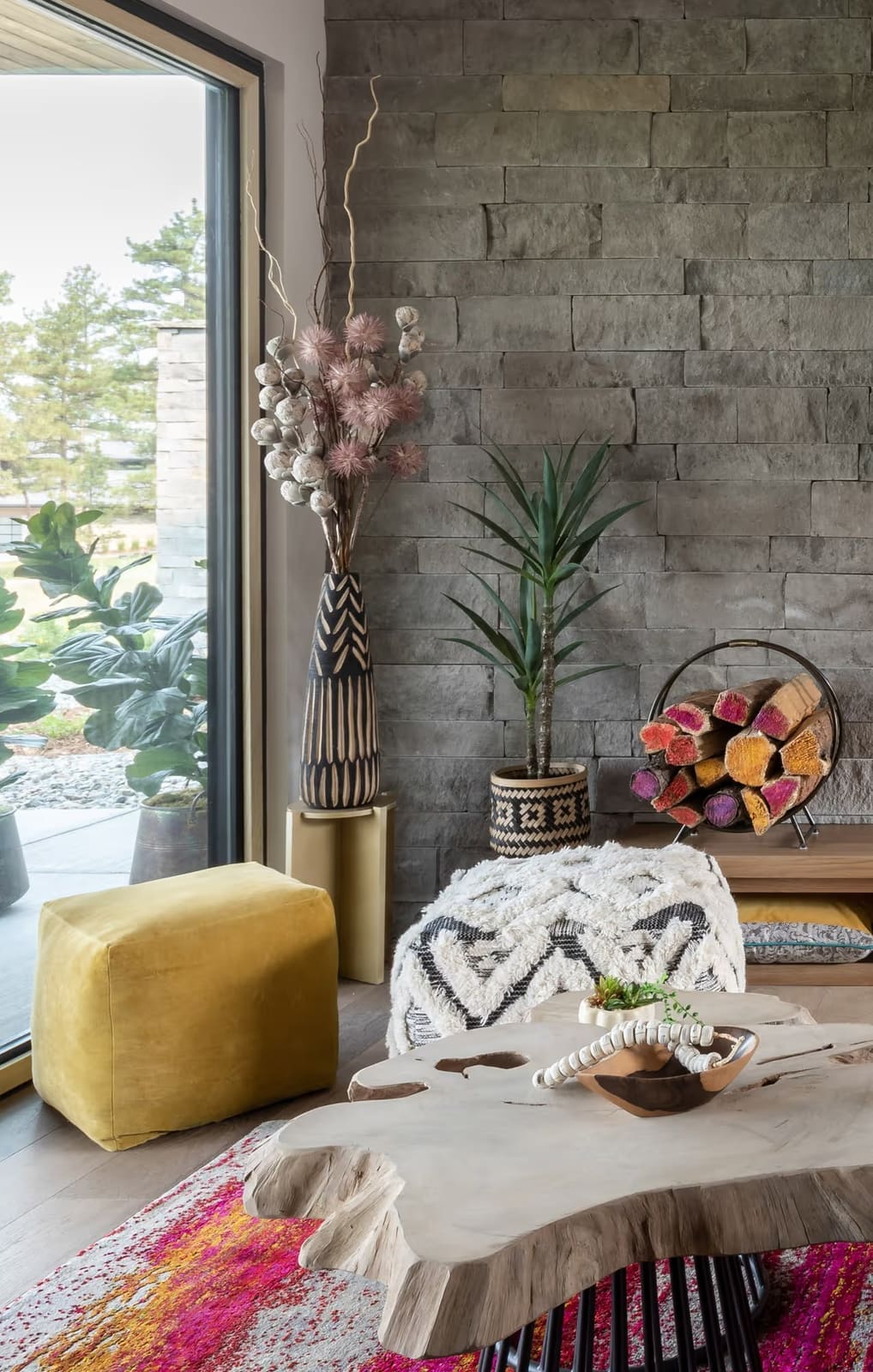 Corner by a glass slider with yellow velvet pouf, black-and-white shag pouf, live-edge table and painted log holder