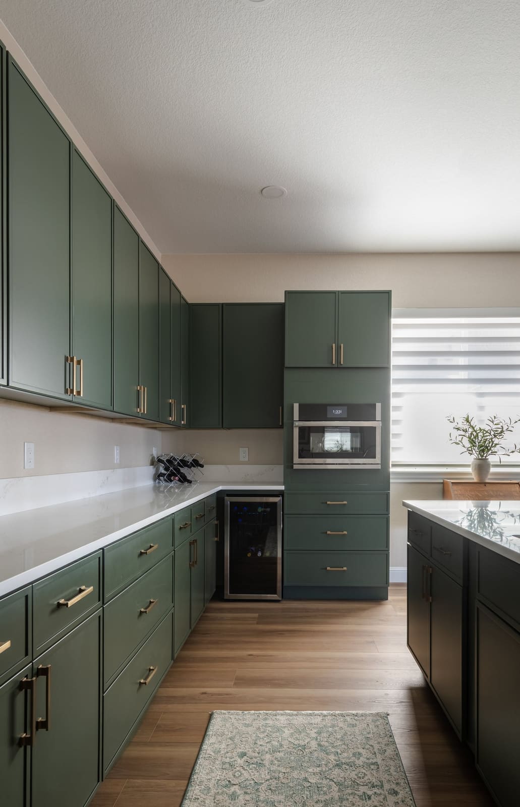 Sage galley run with a wine fridge, wall oven and white quartz counters