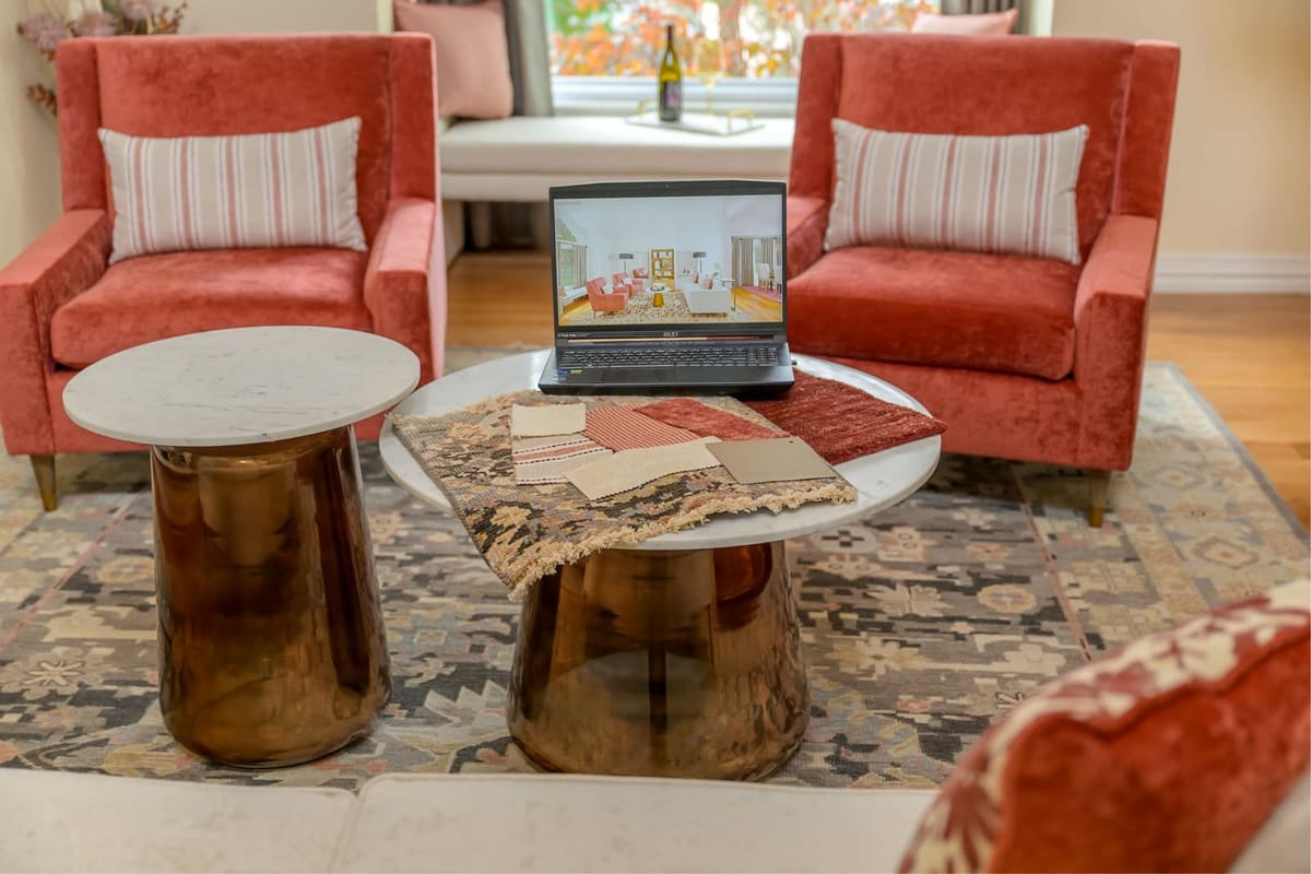 Design presentation with fabric and rug samples and a laptop rendering on marble and bronze nesting tables
