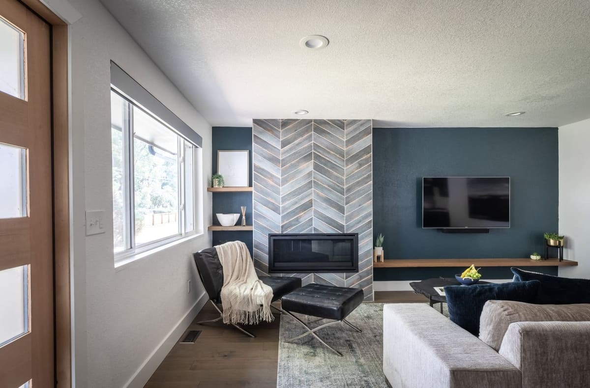 Chevron tile fireplace flanked by floating walnut shelves, a leather lounge chair and white sofa