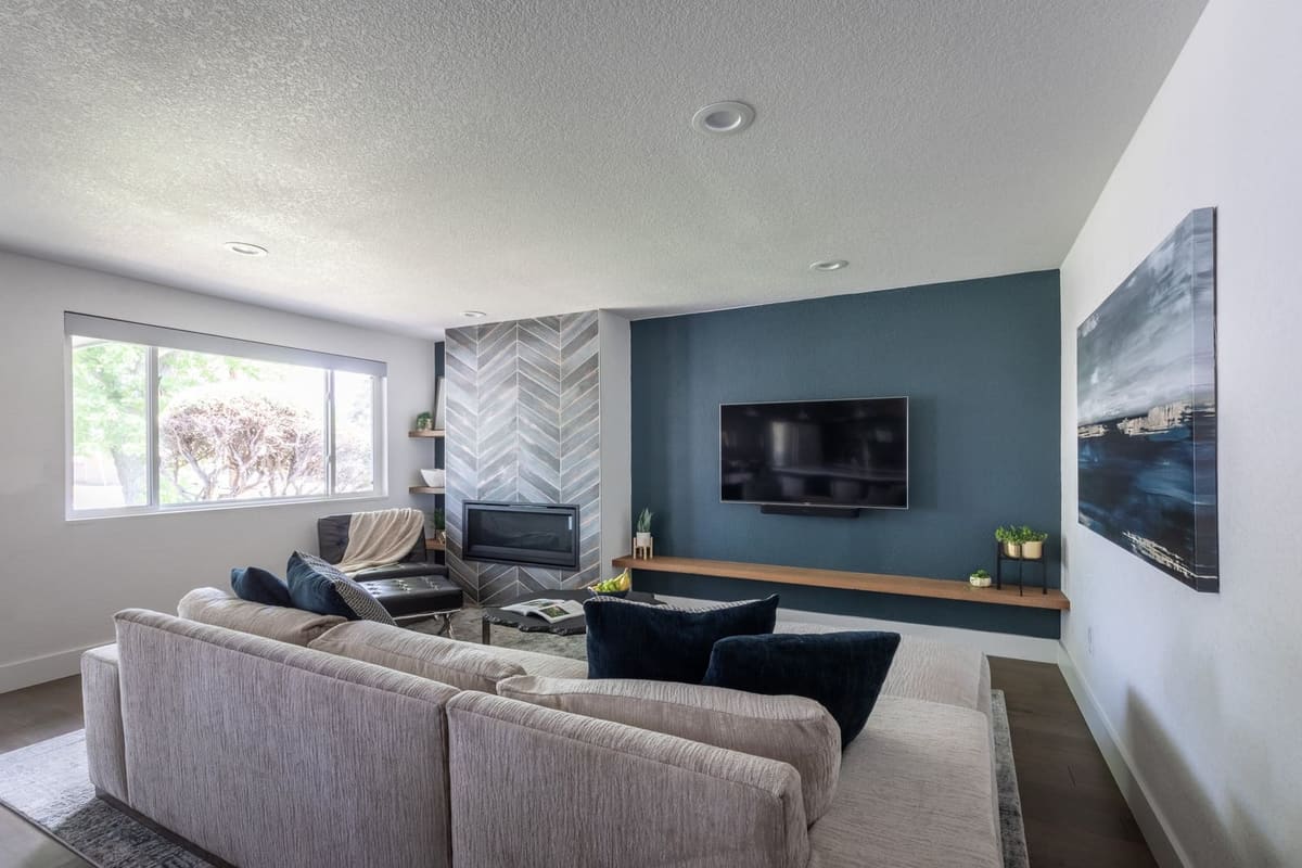 Living room with a gray sectional facing a chevron tile fireplace and navy TV wall