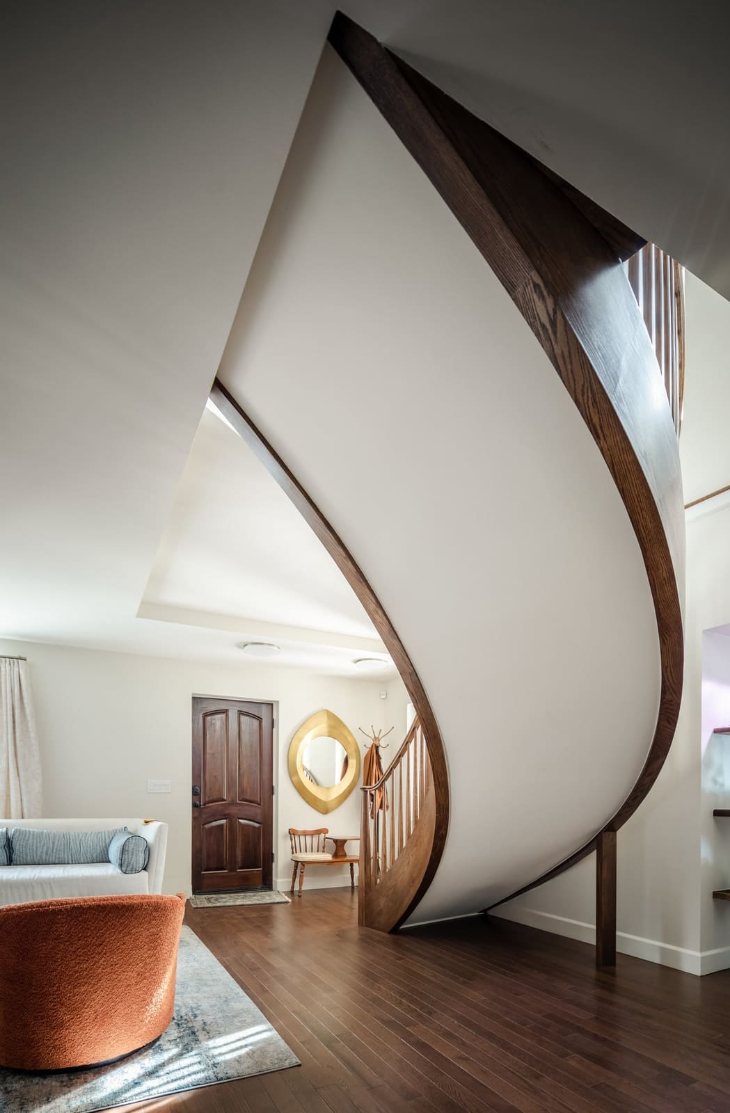 Underside of the sweeping curved staircase above an orange swivel chair